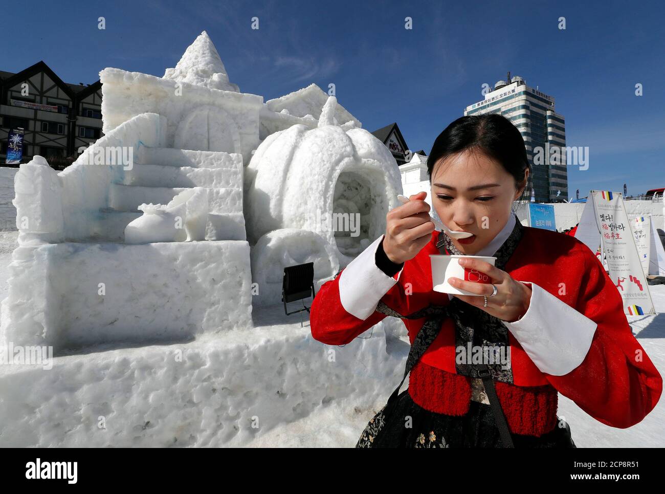 Una mujer vestida con ropa tradicional coreana come de arroz mientras celebra el año Nuevo Lunar entre esculturas de hielo en Pyeongchang, Corea del Sur, 16 febrero de