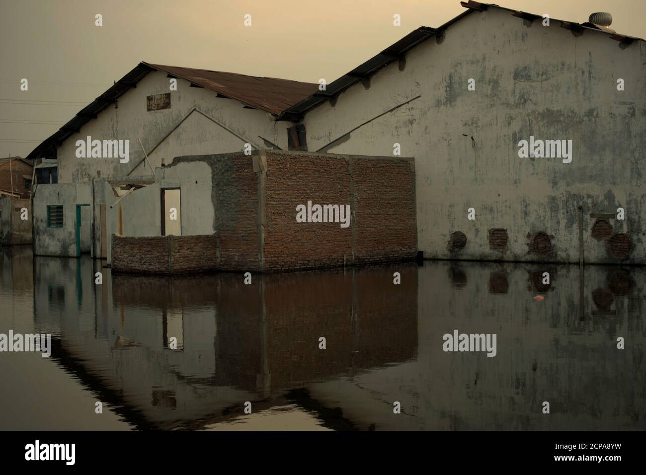 Edificios de almacenes sumergidos en una zona costera que sufren de hundimiento de la tierra e inundaciones de agua de mar. Foto de stock