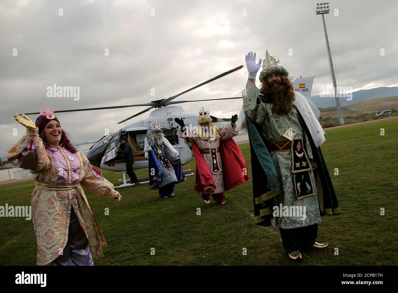 Los hombres vestidos como los tres Reyes Magos y una mujer en un traje de cartero  real se agitan a los niños después de llegar en un helicóptero para  participar en el