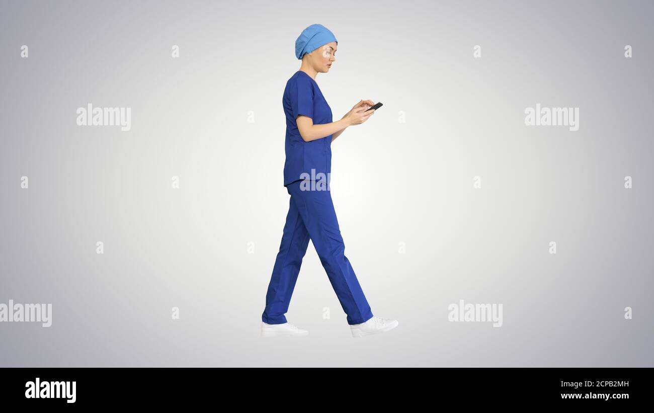 Mujer, doctor o enfermera en uniforme azul usando su teléfono como ella Foto de stock