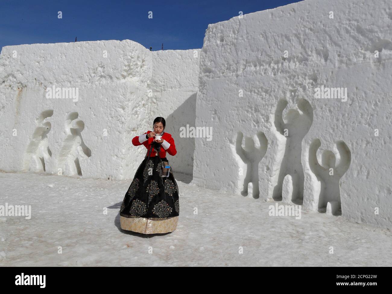Una mujer vestida con ropa tradicional coreana come de arroz mientras celebra el año Nuevo Lunar entre esculturas de hielo en Pyeongchang, Corea del Sur, 16 febrero de