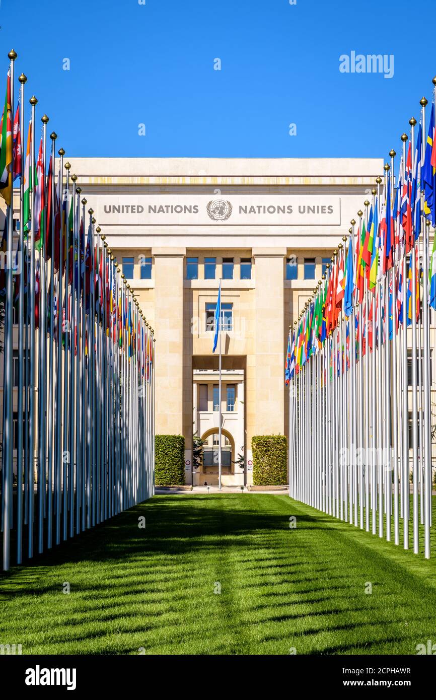 Vista frontal de la avenida de banderas y fachada del Palacio de las Naciones, sede de la Oficina de las Naciones Unidas en Ginebra, Suiza, en un soleado día de verano Foto de stock
