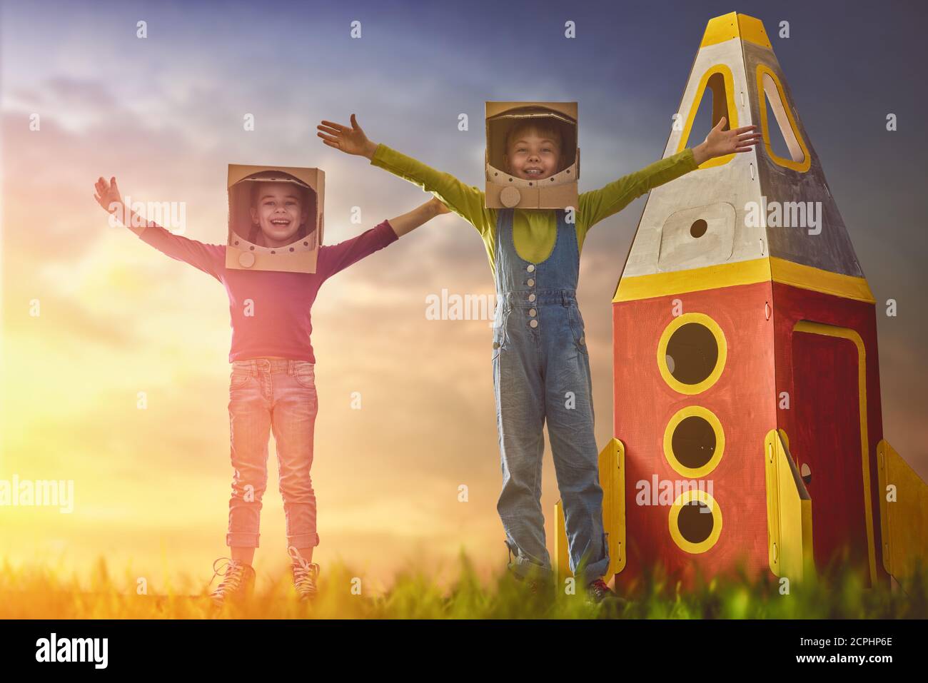 Los niños en astronautas disfrazan con cohetes de juguete jugando y soñando  con convertirse en un hombre espacial. Retrato de niños divertidos sobre un  fondo de cielo estrellado al atardecer Fotografía de