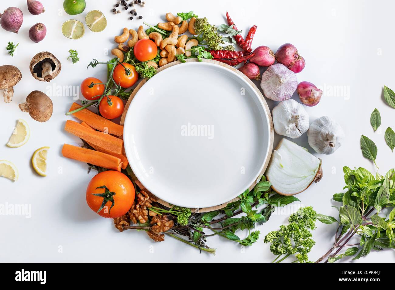 Alimentación saludable. Plato blanco de cerámica rodeado de verduras frescas y saludables, sobre fondo blanco Foto de stock
