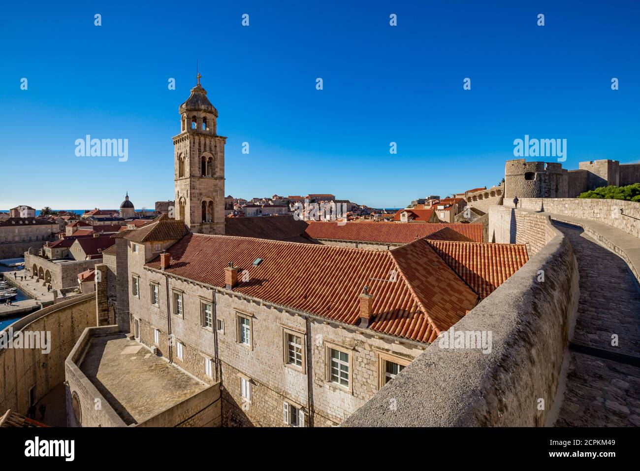 Colorido fortaleza calle escena de paseo, cielo claro día soleado. Torre de la iglesia, edificios de techos. Vista invernal de la ciudad vieja mediterránea de Dubrovnik, famoso viaje europeo y destino histórico, Croacia Foto de stock