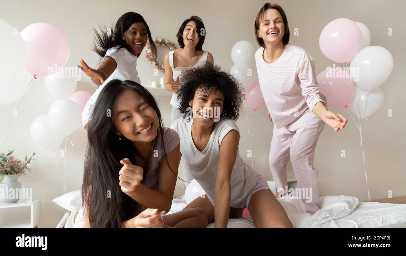 Las jóvenes muy diversas y atractivas niñas multirraciales entretenidas juntas en el dormitorio. Foto de stock