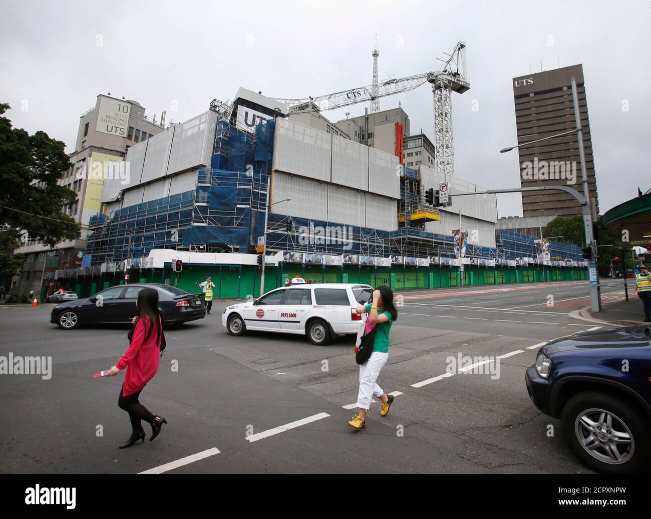 Los peatones pasan por un sitio de construcción en la Universidad de Tecnología de Sydney (UTS), después de que la pluma de izado de una grúa de torre se colapsó en el edificio de abajo, en el centro de Sydney el 27 de noviembre de 2012. Los servicios de emergencia cerraron las calles de los alrededores después de que la grúa incendiara. REUTERS/Tim Wimborne (AUSTRALIA - Tags: EMPRESA DE DESASTRES INDUSTRIAL) Foto de stock