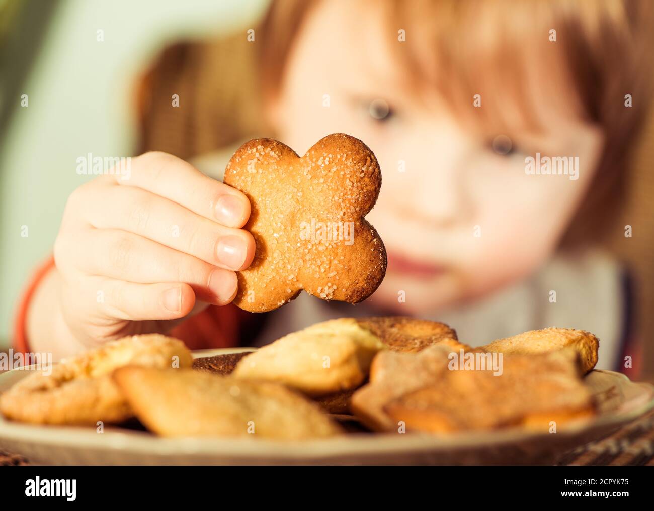 niño tomando galletas dulces del plato Foto de stock