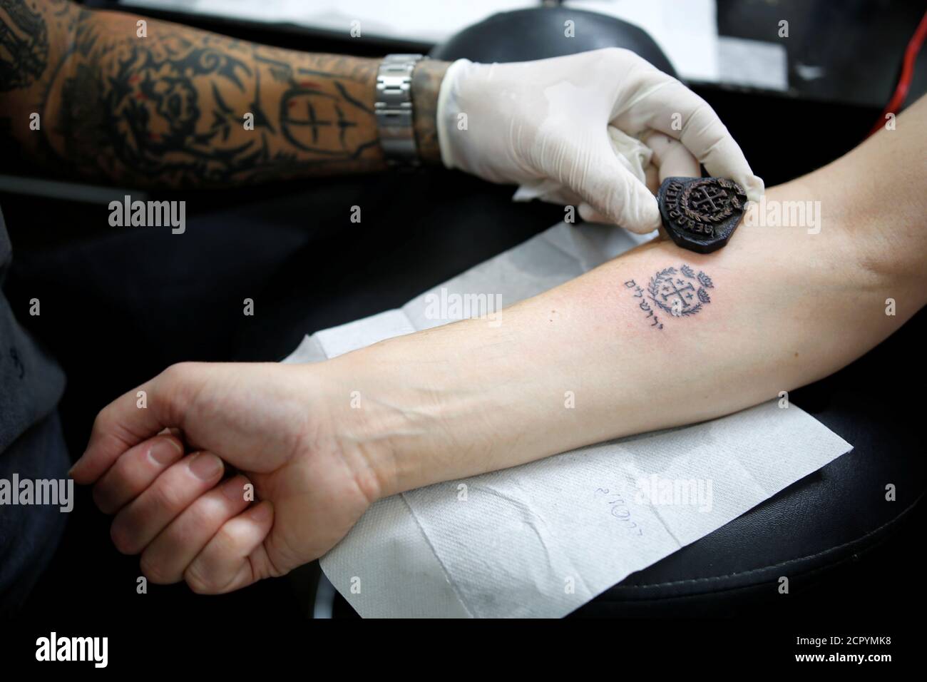 El artista de tatuajes Wassim Razzouk, que continúa la tradición de su  familia de entintar peregrinos cristianos con tatuajes antiguos, sostiene  un antiguo sello de tatuaje de madera cerca de un tatuaje