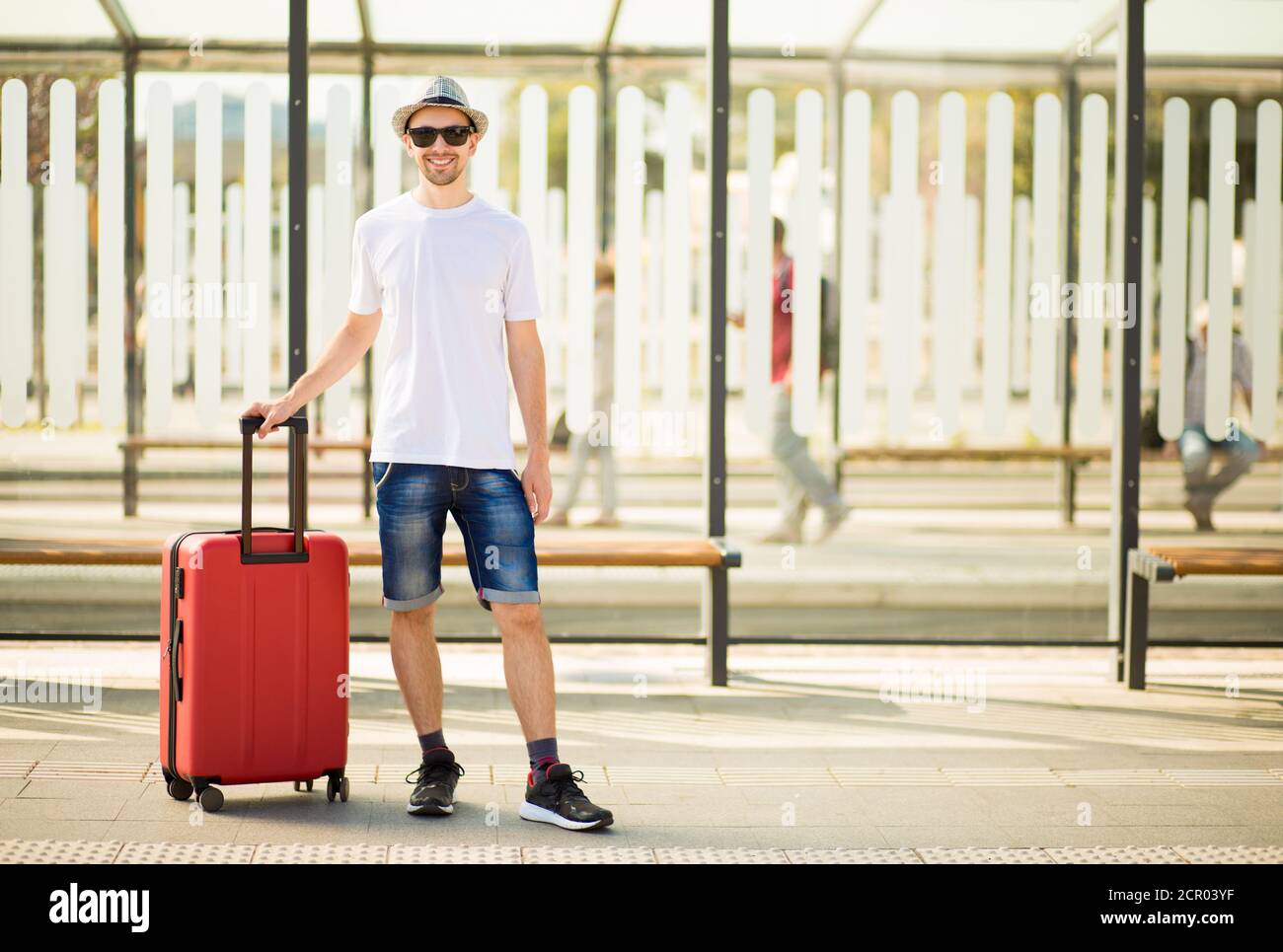 Un hombre de viaje con una maleta con ropa de estilo elegante esperando  para el transporte. Espacio de copia Fotografía de stock - Alamy