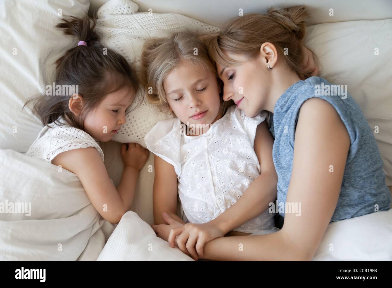 Madre con niños durmiendo tranquilamente en la cama Foto de stock