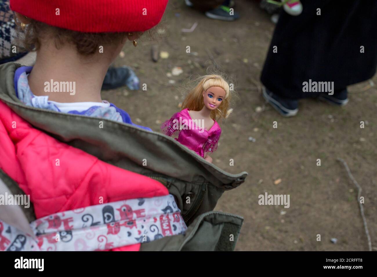 Una joven lleva una muñeca Barbie mientras ella y otros migrantes esperan  en fila para ser engañados por la policía después de cruzar la frontera  desde Macedonia, en Miratovac, Serbia 15 de