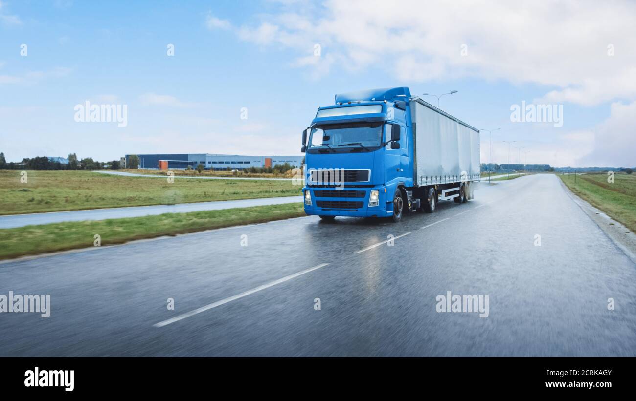 Semi-camión largo con remolque de carga lleno de mercancías viaja en la carretera. Día conduciendo a través del continente a través de la lluvia. Venta al por menor industrial Foto de stock