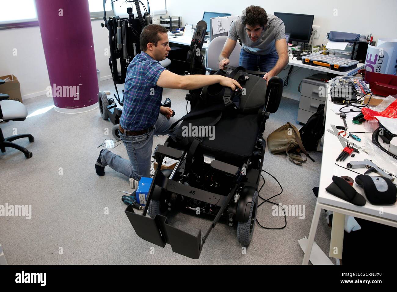 Employees work on a wheelchair developed by Israeli company UPnRIDE Robotics,  that enables paralysed people with limited function in their arms to stand  upright, during a demonstration at their offices in Yoqneam,