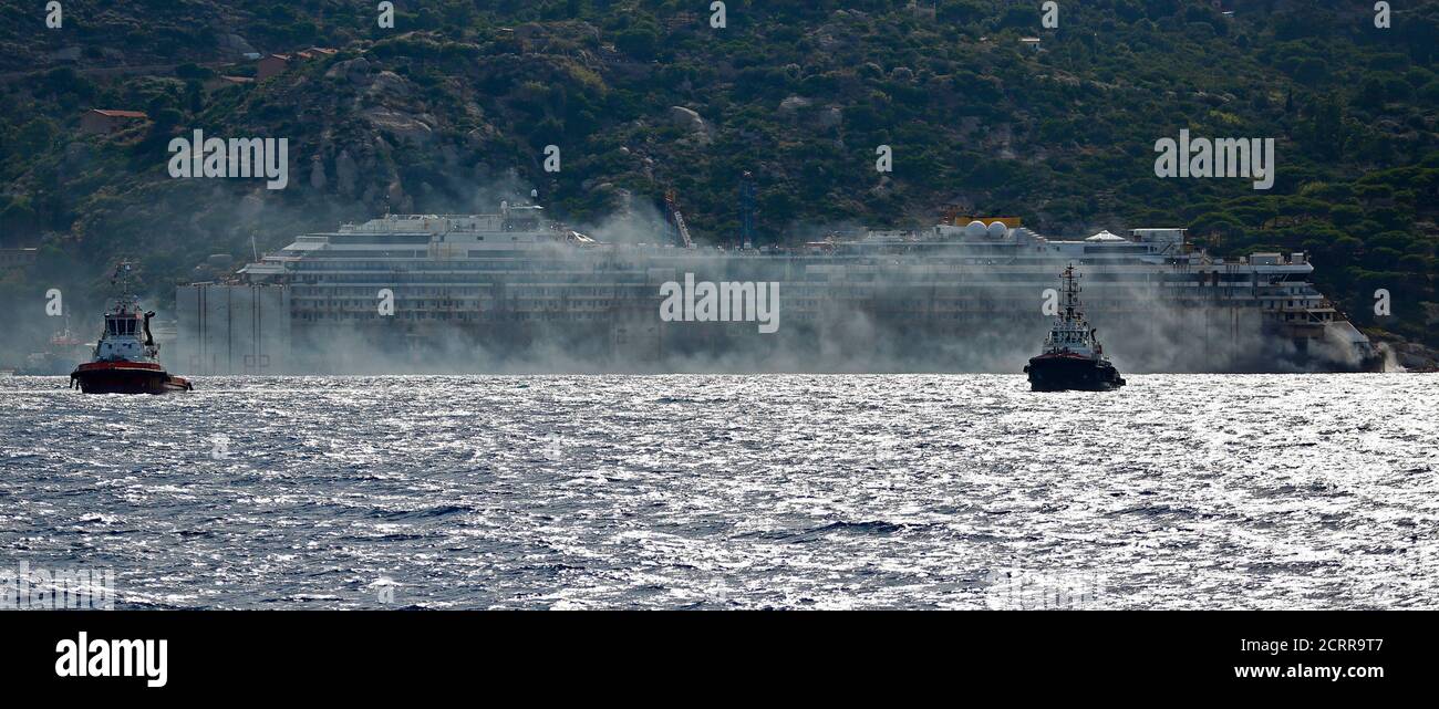 Black smoke comes out from the back of the Costa Concordia cruise liner during its refloat operation at Giglio harbour July 22, 2014. The massive hulk of the Costa Concordia is nearly ready to be towed away from the Italian island where it struck a rock and capsized two-and-a-half years ago, killing 32 people, officials said on Sunday. The 114,500-tonne Concordia has been slowly lifted from the sea floor since Monday, when salvagers began pumping air into 30 large metal boxes, or sponsons, attached around the hull. A convoy of 14 vessels will then tow the Concordia to a port near Genoa, where Foto de stock