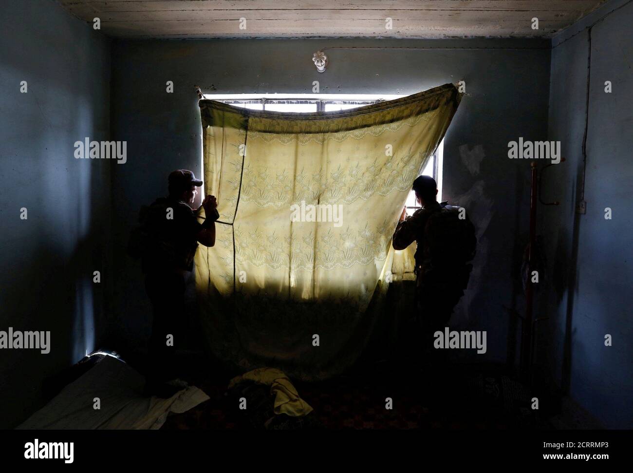 Miembros de las fuerzas del Servicio contra el Terrorismo iraquí (CTS) miran las posiciones de los militantes del Estado Islámico durante los enfrentamientos en el oeste de Mosul, Irak, el 15 de mayo de 2017. Siddiqui danés: 'En mayo, acompañaba a un comandante del Servicio contra el Terrorismo, una fuerza de seguridad iraquí de élite entrenada por los Estados Unidos, durante la batalla para tomar el control de Mosul Occidental. Llegamos a una pequeña casa en la primera línea después de caminar a través de los agujeros en las paredes entre las casas. Los francotiradores del Estado Islámico disparaban a unos cientos de metros de distancia. La gente que una vez vivió allí se fue rápidamente, dejando la ropa y los juguetes raspando Foto de stock