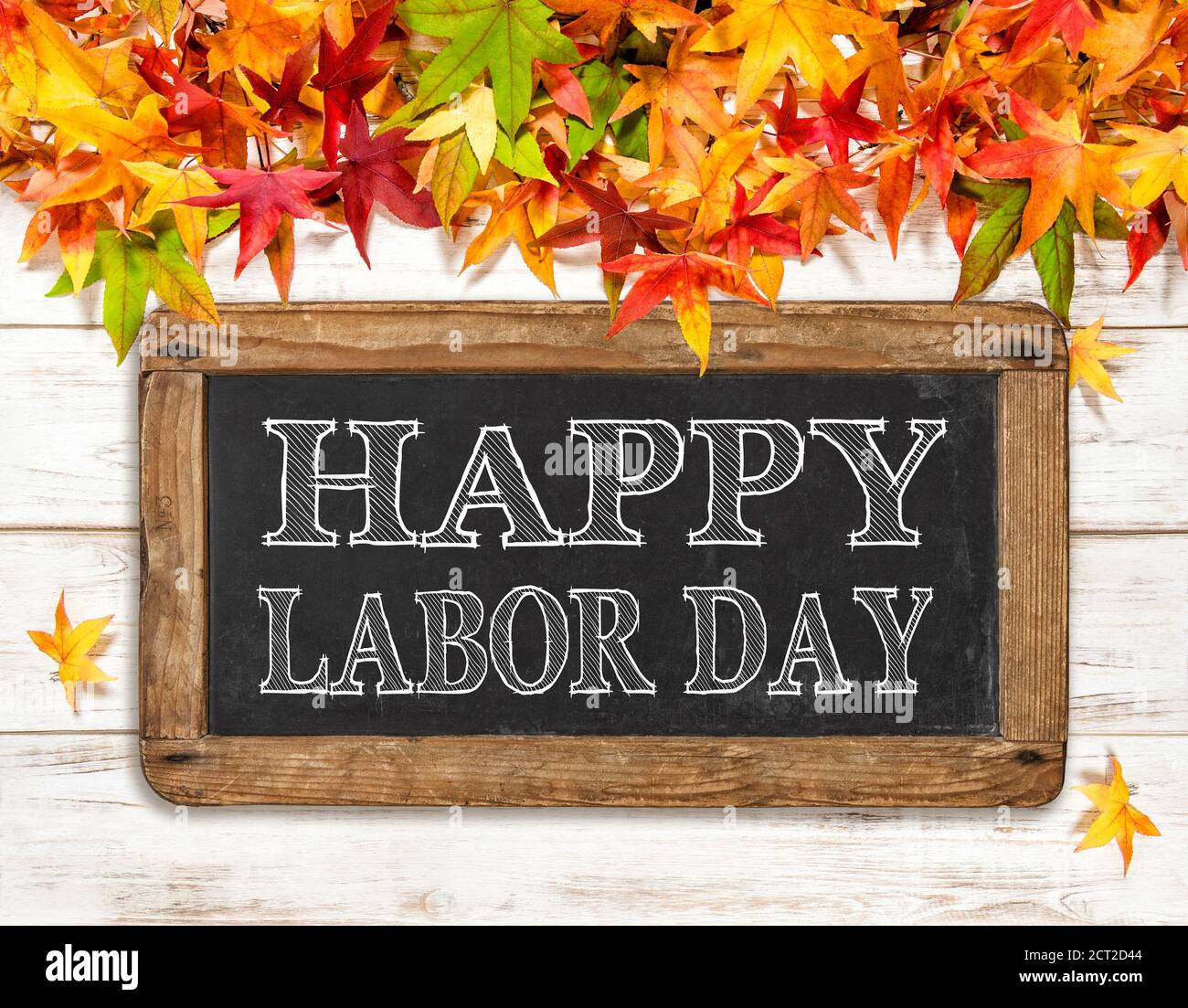 Feliz día del Trabajo. Hojas de otoño y pizarra sobre fondo de madera brillante Foto de stock