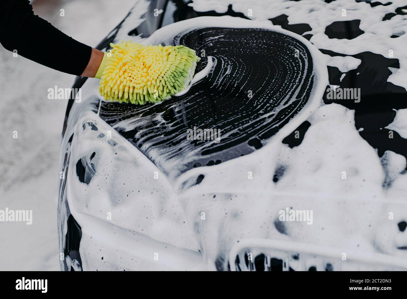 mans mano sujetando una esponja para lavar el coche. auto negro con pompas  de jabón. concepto de limpieza. trabajador limpiando automovil 13185225  Foto de stock en Vecteezy