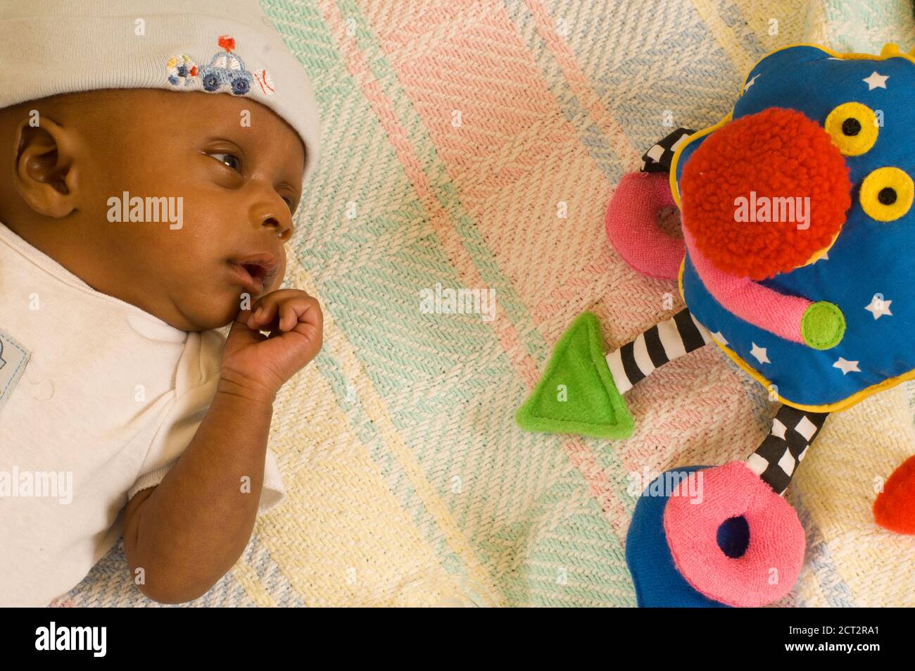 6 semanas recién nacido niño un mes alerta prematura mirando el juguete de colores, usando gorra Foto de stock