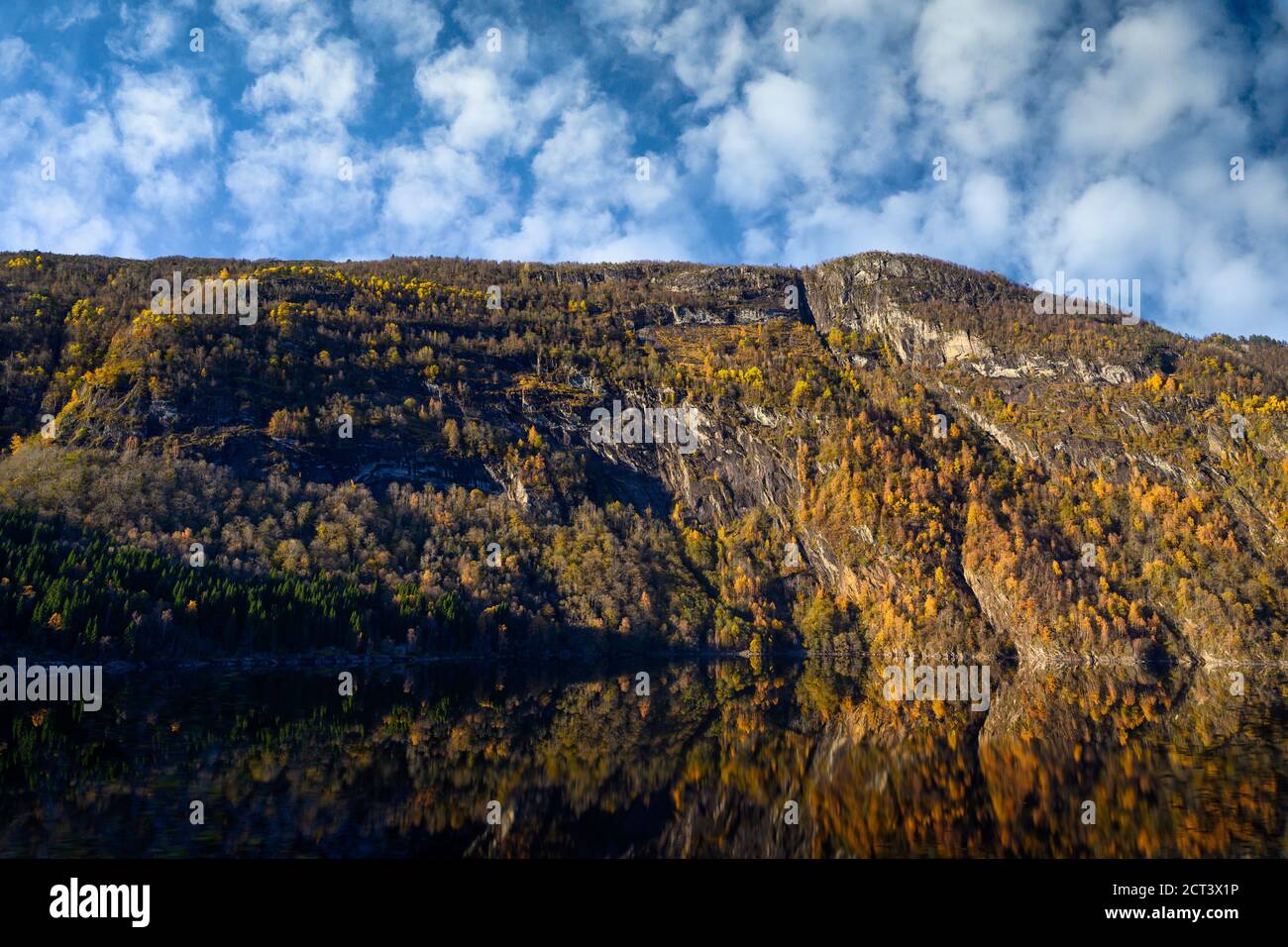Las montañas en otoño cambian el color de las hojas para cambiar a reflejos amarillos y naranjas en el agua. Es una hermosa vista natural de Noruega. Foto de stock