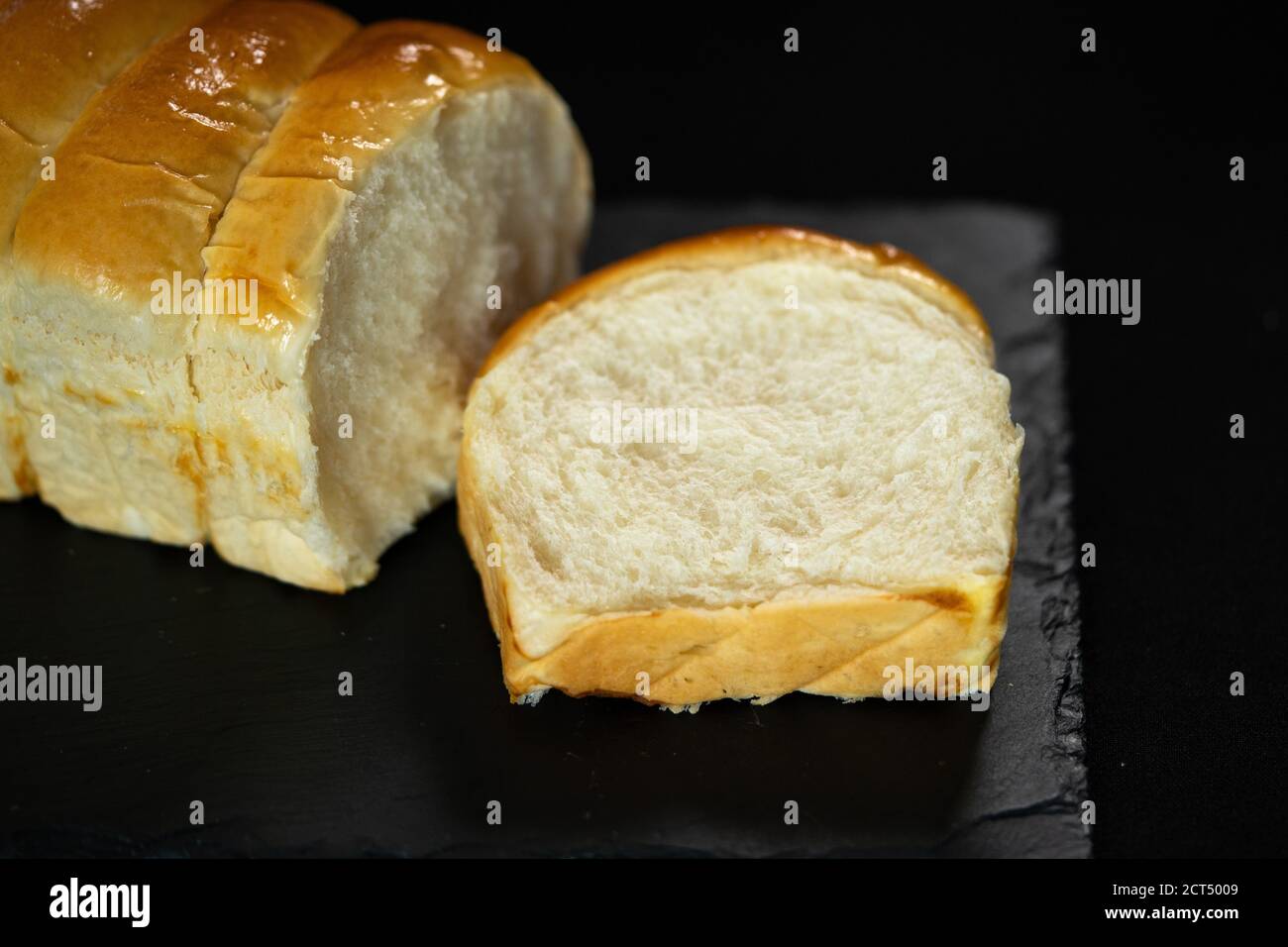 Cortar pan blanco, pan de pan sobre fondo negro. Espacio de copia. Concepto de panadería. Foto de alta calidad Foto de stock