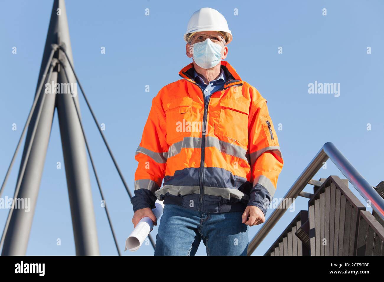 Arquitecto o ingeniero con máscara facial y ropa protectora caminando abajo - foco en la cara Foto de stock