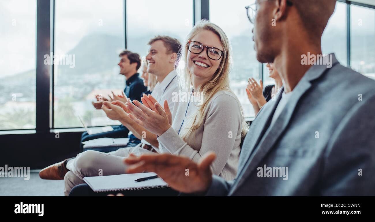 Grupo de empresarios aplaudiendo al orador después de la presentación de la conferencia. Hombres de negocios y mujeres sentados en el público golpeando las manos. Foto de stock