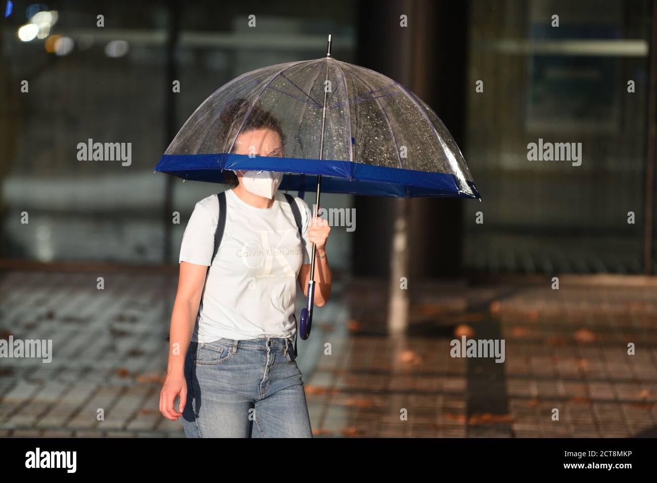 Barcelona, España. 21 de septiembre de 2020. Una mujer joven que lleva un  paraguas como protección contra la lluvia es vista usando una mascarilla  como medida preventiva contra la propagación del coronavirus.