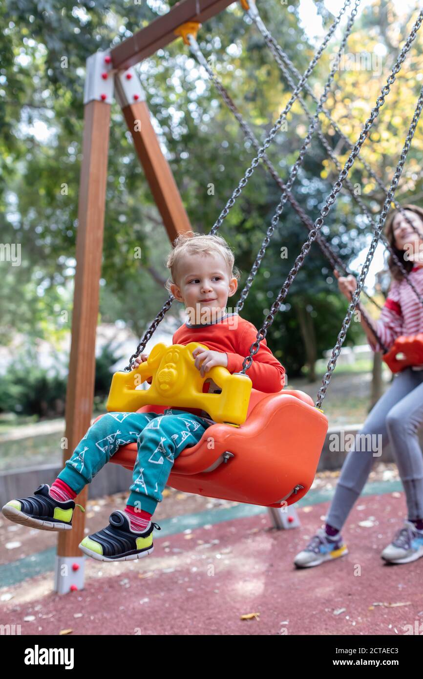 Madre con hijo Diversión Swinging Together at Playground Foto de stock