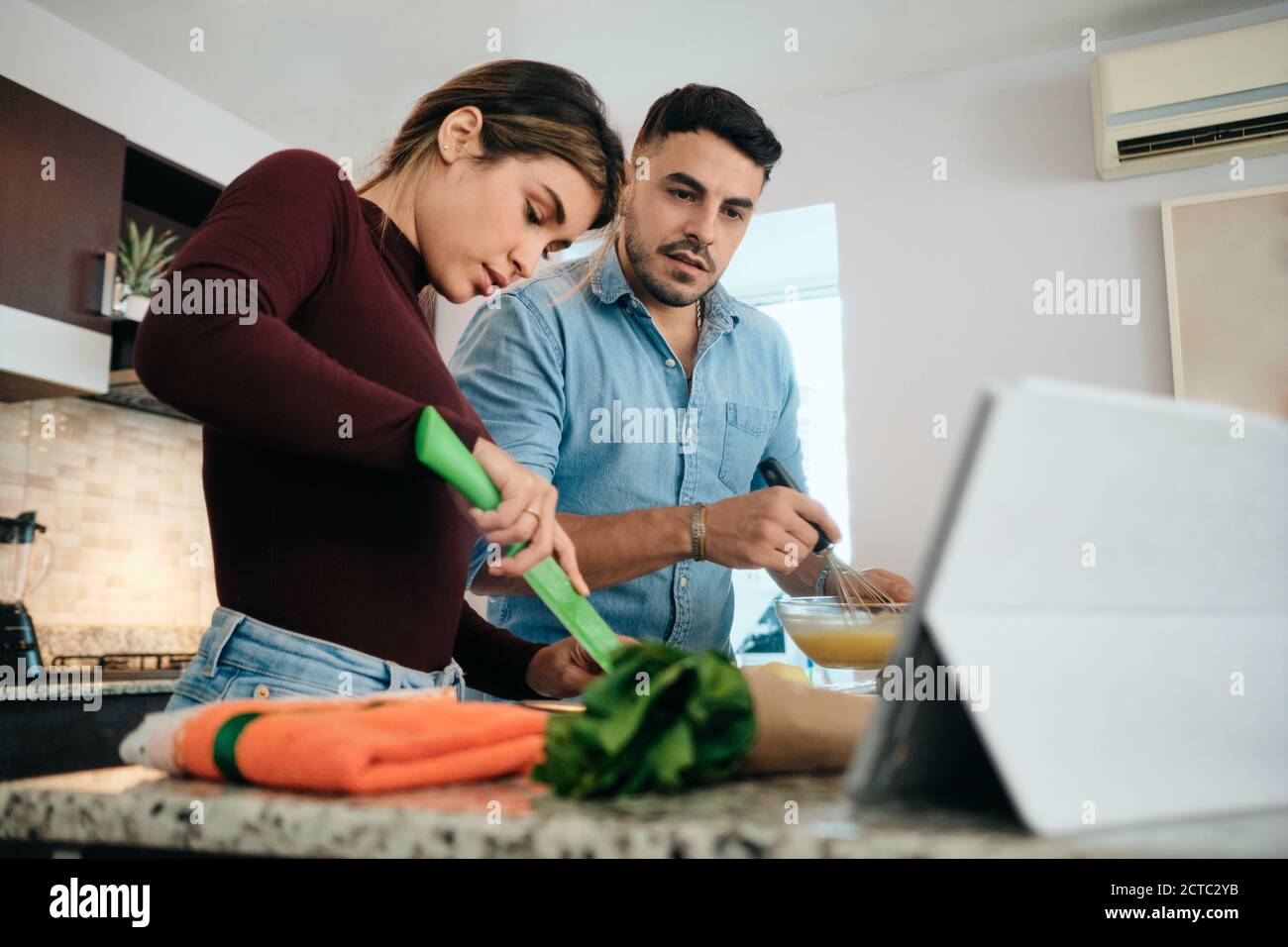 Pareja cocinando juntos observando Tutorial para Receta Foto de stock