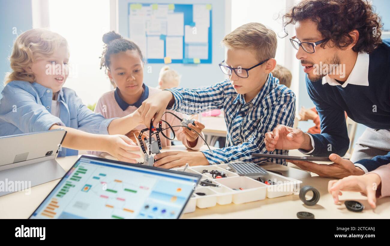 Aula de Robótica de la Escuela Primaria: Grupo diverso de niños brillantes  con Maestro entusiasta edificio y Robot de Programación. Niños aprendiendo  Fotografía de stock - Alamy