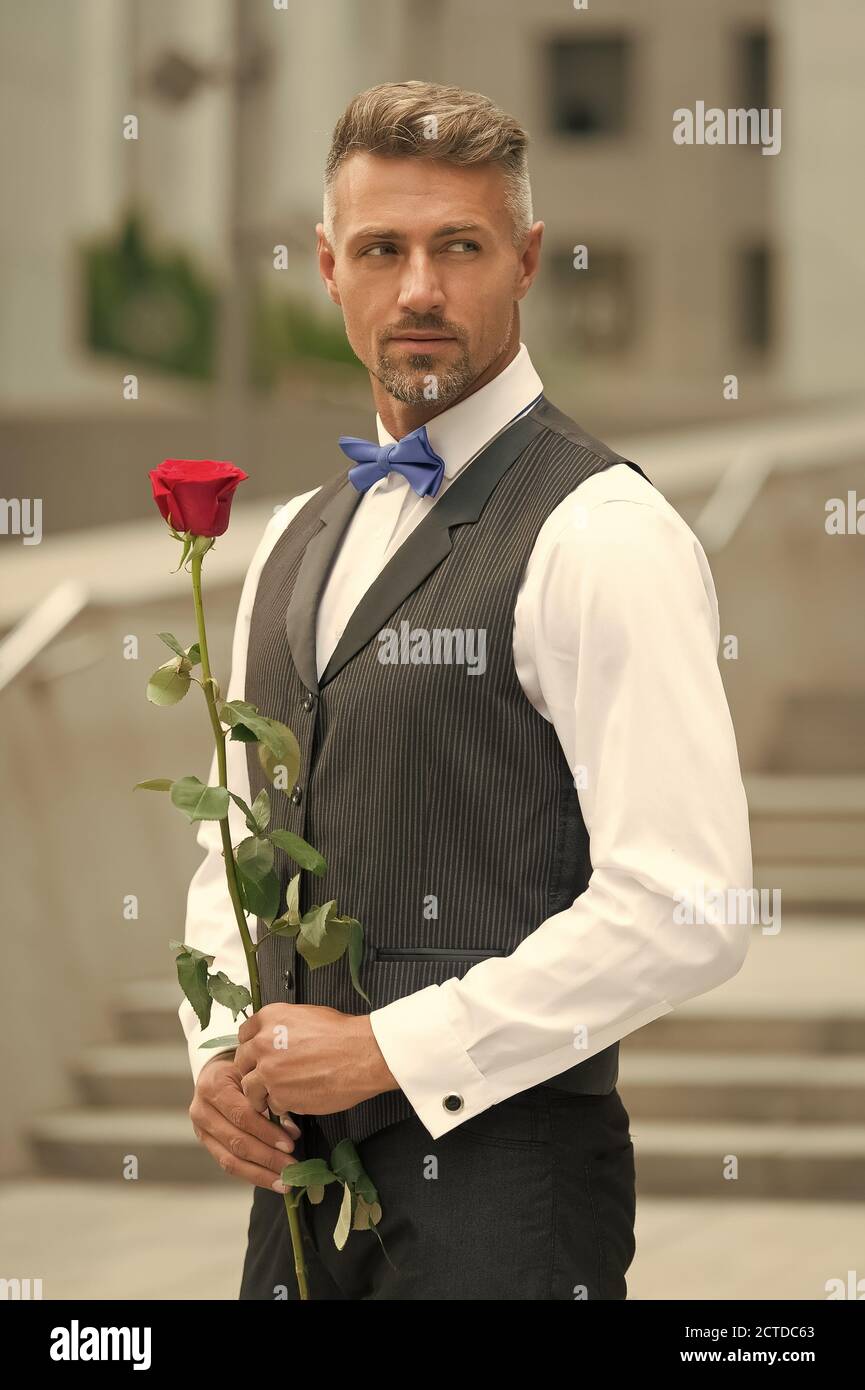 Caballero real celebración aumentó en mano. ser mi Valentín. Día de las  mujeres concepto. Hombre con rosa flor. Hombre de vestimenta formal la  celebración de rosa roja. Poner en una pajarita. mens