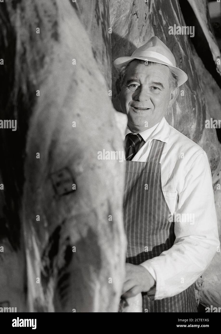 Carnicero de pie entre la carne picada - imagen histórica de la década de 1990 Foto de stock
