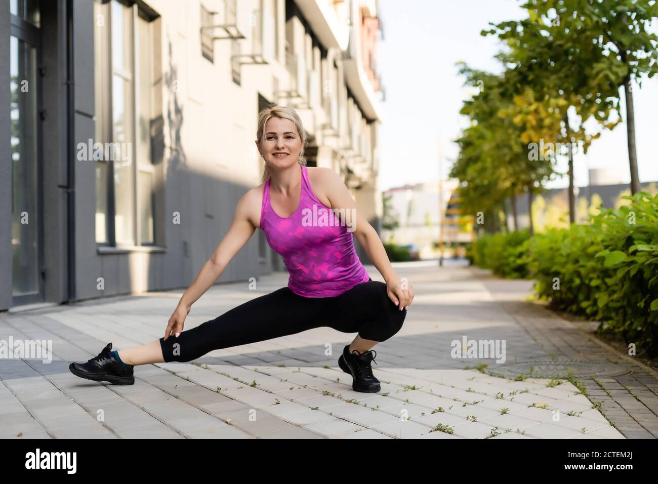 Deporte mujer de fitness de moda ropa deportiva hacer yoga ejercicio de  fitness en la calle de la ciudad sobre fondo gris concreto. Ropa deportiva  al aire libre y Fotografía de stock 