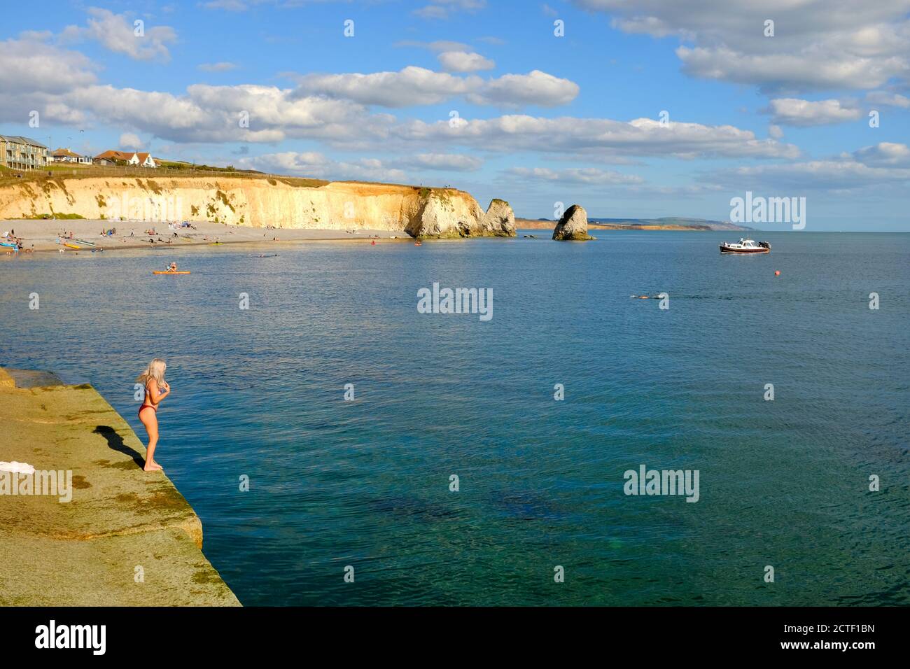 Freshwater Bay Isla de Wight nadar buen clima agosto banco la chica del fin de semana de vacaciones está a punto de entrar en la vista del agua al otro lado de la bahía Foto de stock