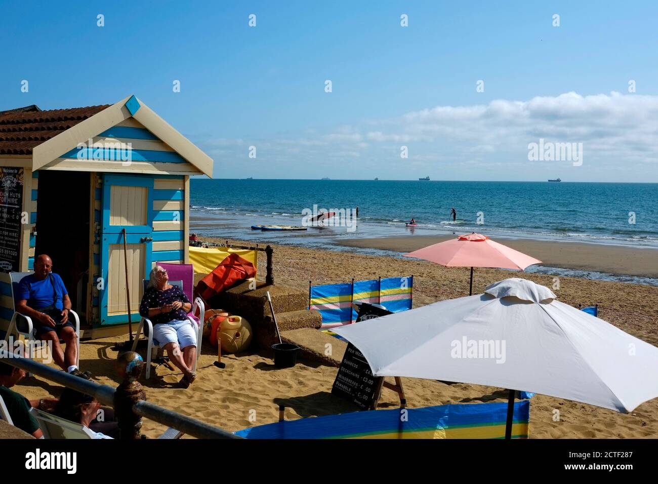 Sandown frente al mar Isla de Wight cortavientos tumbonas sombrillas  tumbonas en la playa en un día soleado y brillante de playa longshoreman's.  cabaña Fotografía de stock - Alamy
