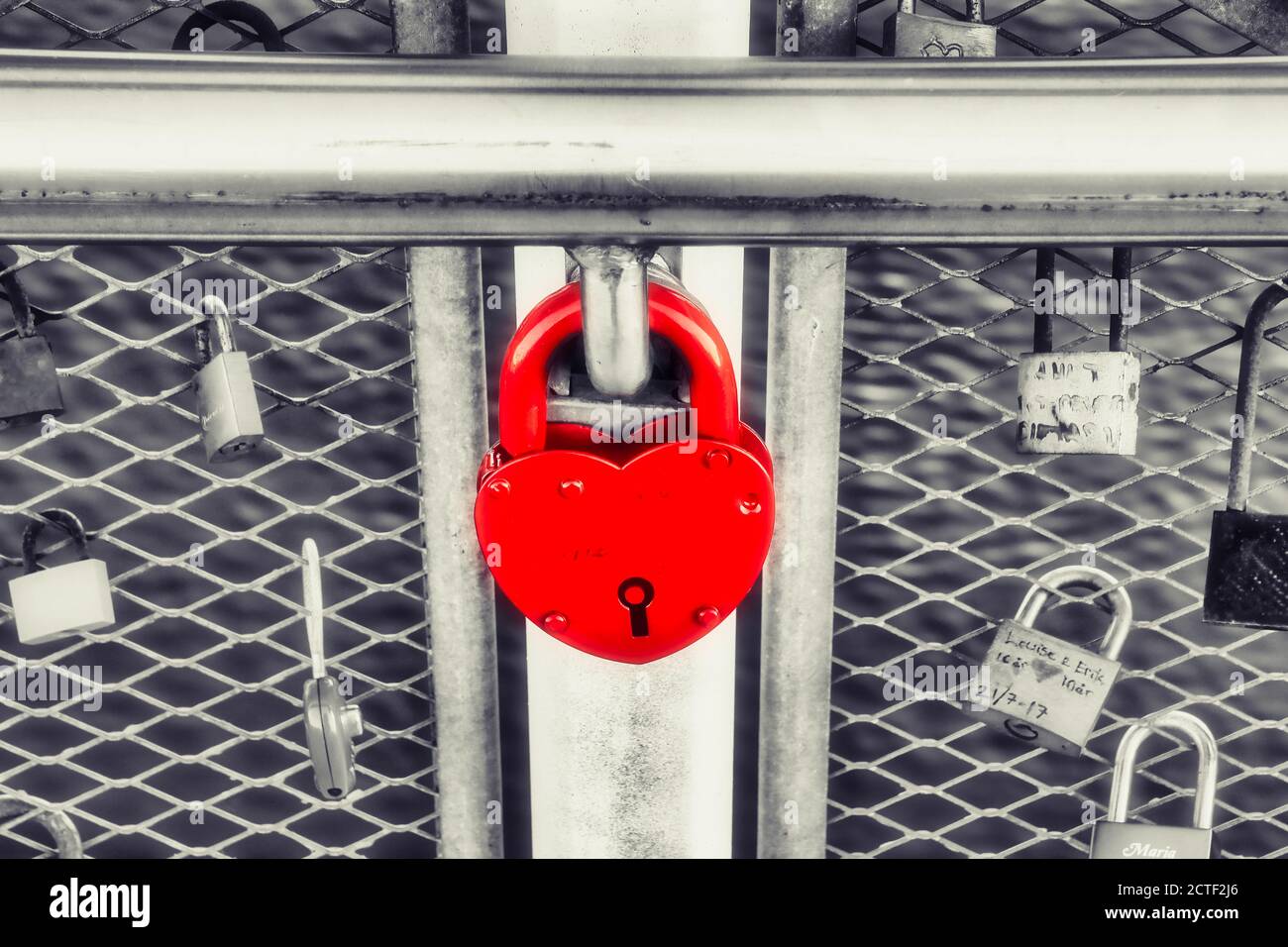Candado rojo grande en forma de corazón con otras cerraduras de amor en un puente de candado de amor peatonal en Helsinki, Finlandia. Color selectivo. Foto de stock