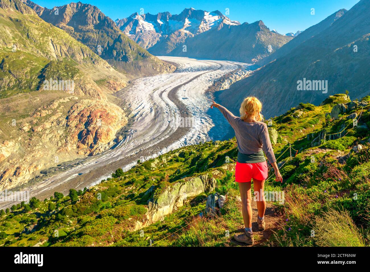 Glaciar Aletsch desde el mirador de Moosfluh en verano, Cantón de Valais, Suiza, Europa. La mujer de excursionistas señaló el glaciar alpino. Al aire libre Foto de stock