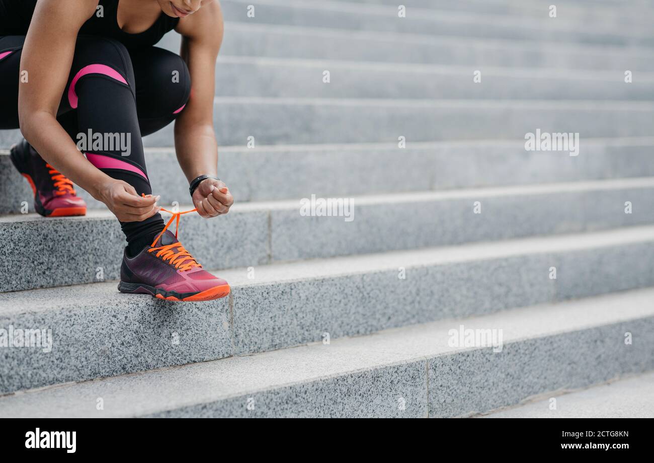 Actividad urbana. Mujer afroamericana en ropa deportiva que ata cordones en  las zapatillas de deporte para el entrenamiento Fotografía de stock - Alamy