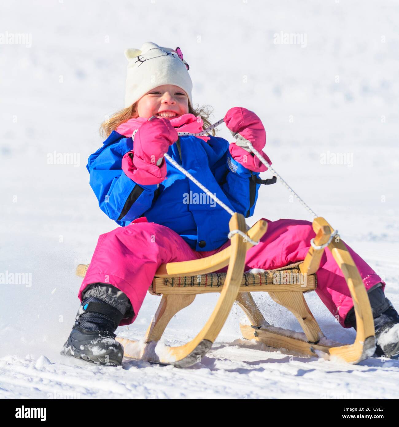 Mujer joven con sled vestida con ropa de invierno casual. Lindo gracioso  mestizos caucásicos mujer asiática sentado en el trineo retro cerca de  nieve cuesta abajo. Una mujer que padece en un
