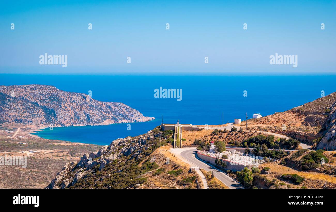 Vista panorámica del cementerio del pueblo de Menetes y Memorial de Guerra, con la bahía de Pigadia en el fondo, la isla de Karpathos, Grecia Foto de stock