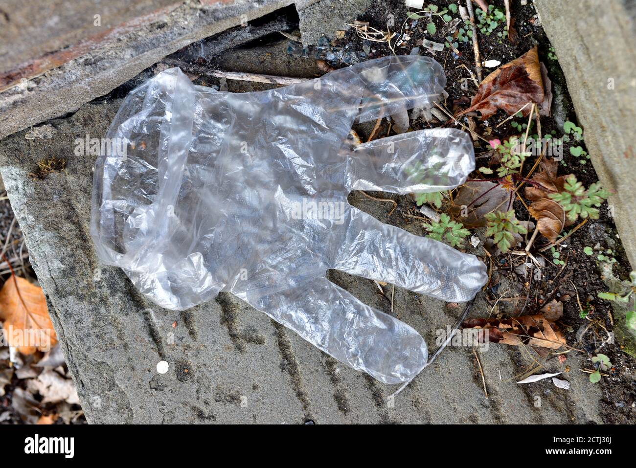 Guantes de plástico desechables desechados como residuos en el pavimento Foto de stock