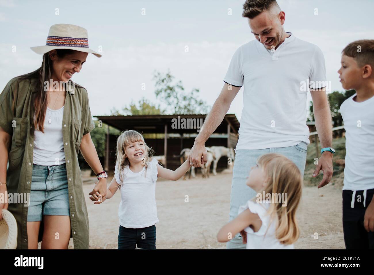 Padres sonriendo hablando con hijas mientras están de pie contra el cielo Foto de stock