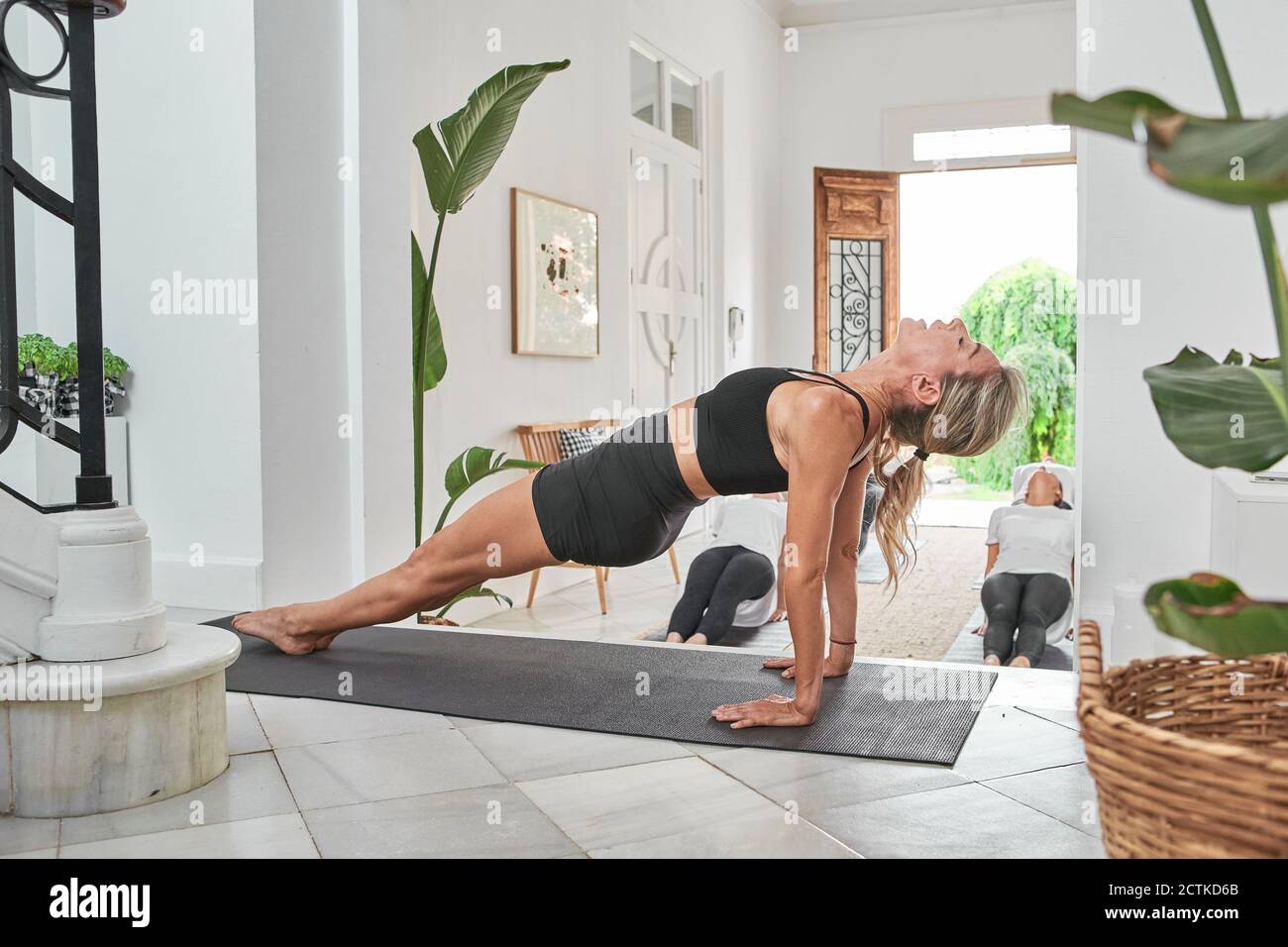 Instructor de yoga con mujeres practicando posición de tabla ascendente en la salud club Foto de stock
