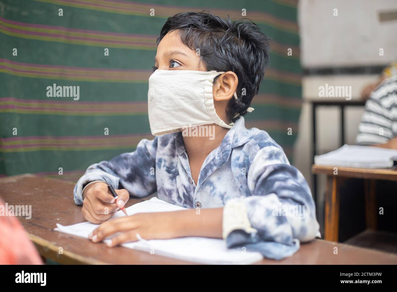 Estudiantes de niños indios que estudian en el salón de clases usando máscara manteniendo el distanciamiento social mira la cámara, reabre la escuela durante la pandemia de covid19, nueva norma Foto de stock