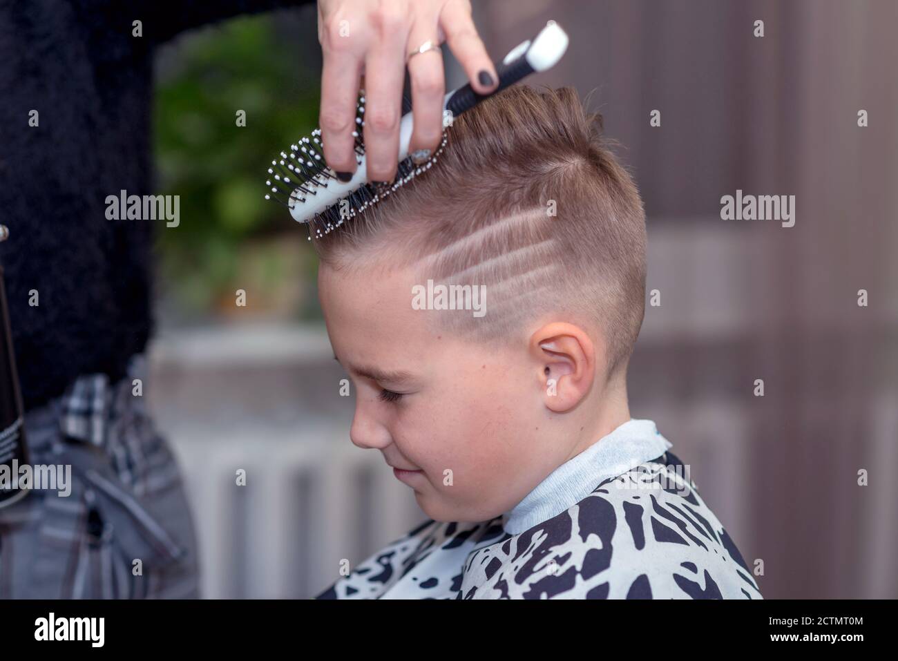 Vista lateral bonito niño europeo conseguir peinado en barbershoppeluquero  hace un peinado para un niño Fotografía de stock  Alamy