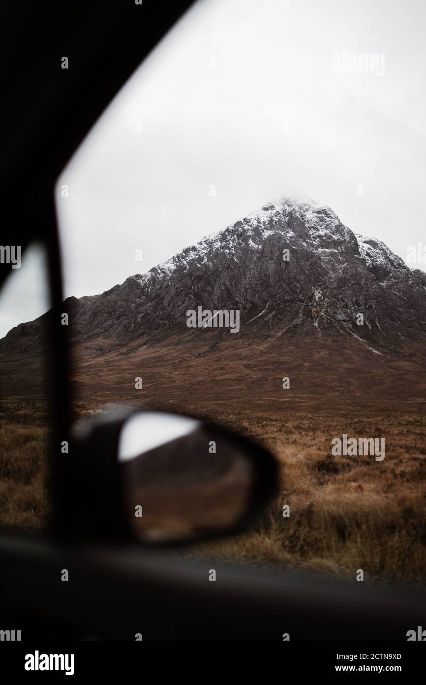 Vista increíble de la cima rocosa de la montaña con nieve en el otoño Desde la ventana del coche en Scottish Highlands Foto de stock