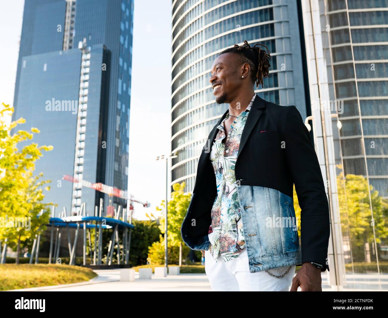 Determinado hombre negro ropa de lujo caminando lo largo del edificio de vidrio en la ciudad y mirando hacia fuera Fotografía de stock - Alamy