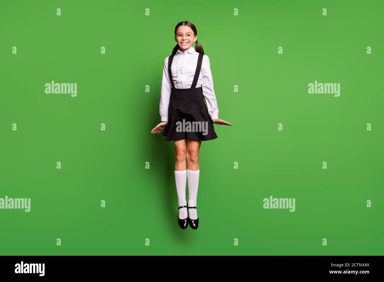 Foto retrato de la colegiala saltando directamente usando calcetines  blancos aislado sobre fondo de color verde vivo Fotografía de stock - Alamy
