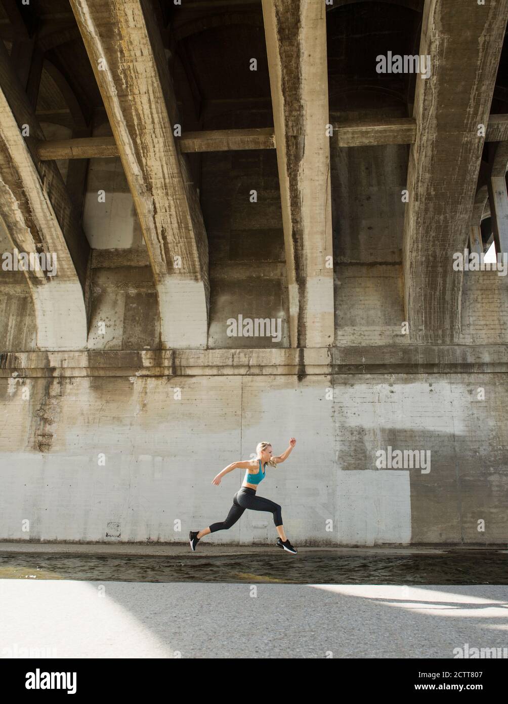 Usa, California, los Angeles, Sporty mujer corriendo por debajo del puente Foto de stock